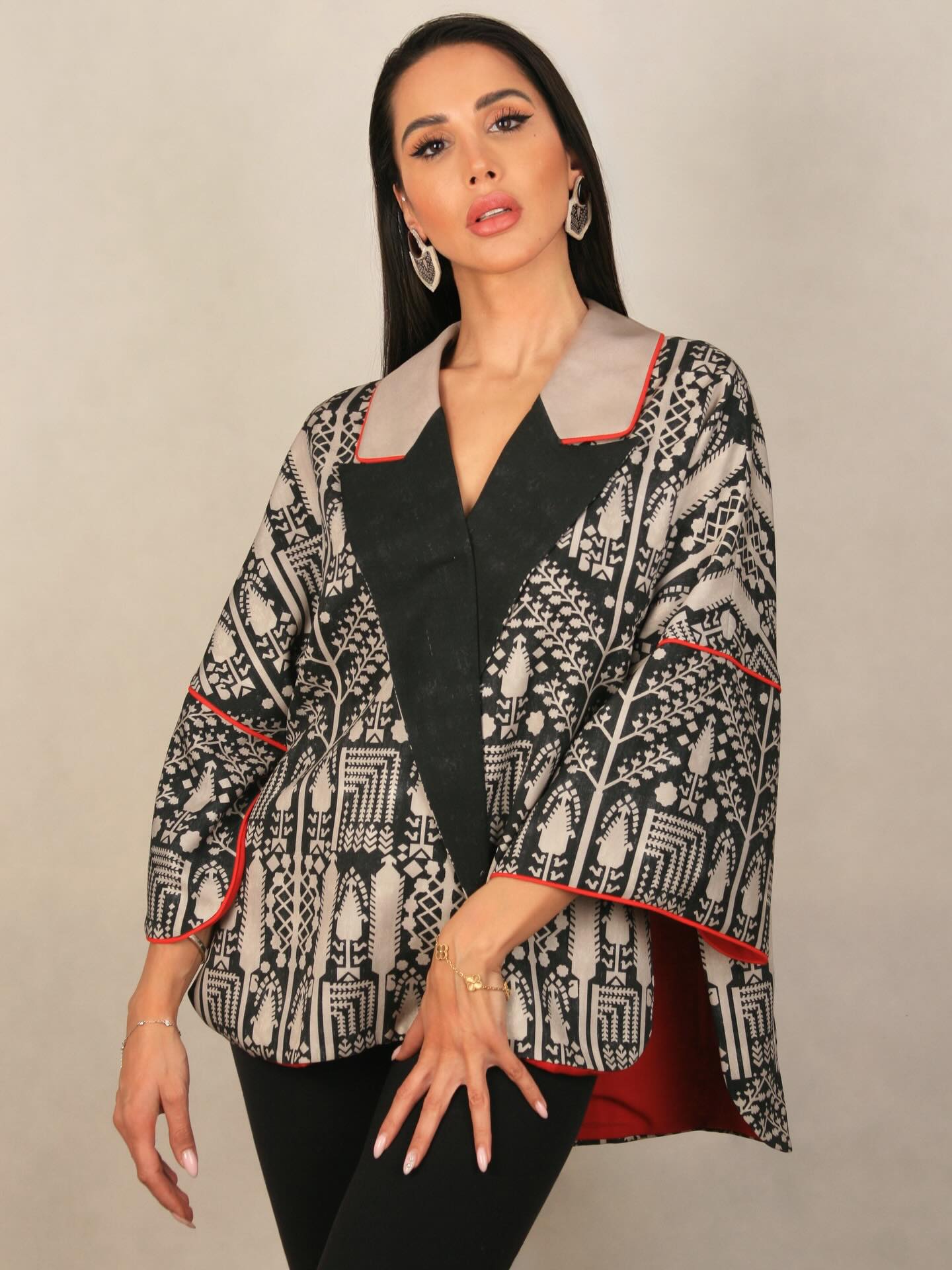 Somayeh en veste ample à motifs noirs et beiges, bordée de rouge